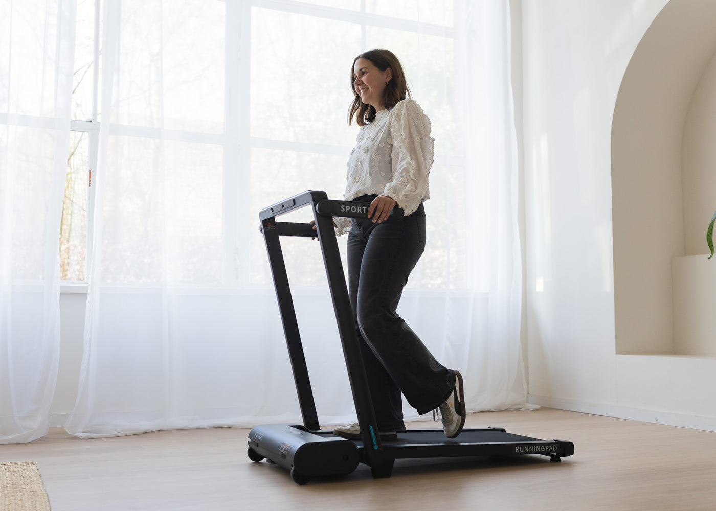 Sanne wandelt op haar RunningPad Pro voor het raam